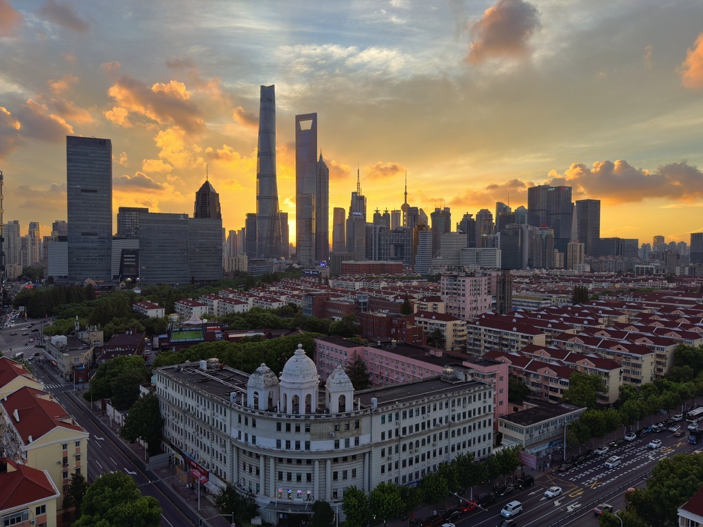 上海城市天际线在金色夕阳下展开，近处是成片的城市街区