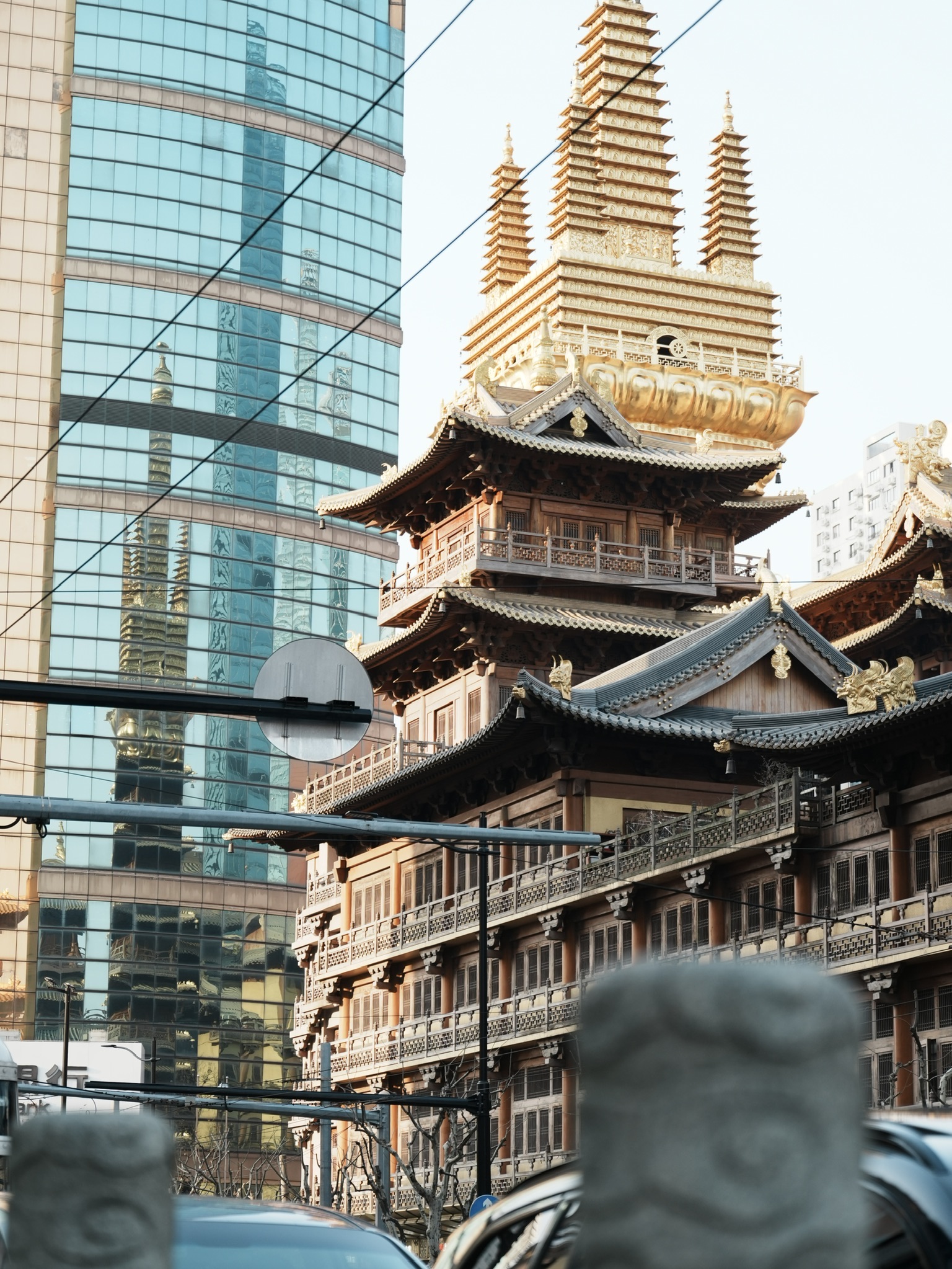 传统寺庙建筑与蓝色玻璃幕墙在城市街道中并置